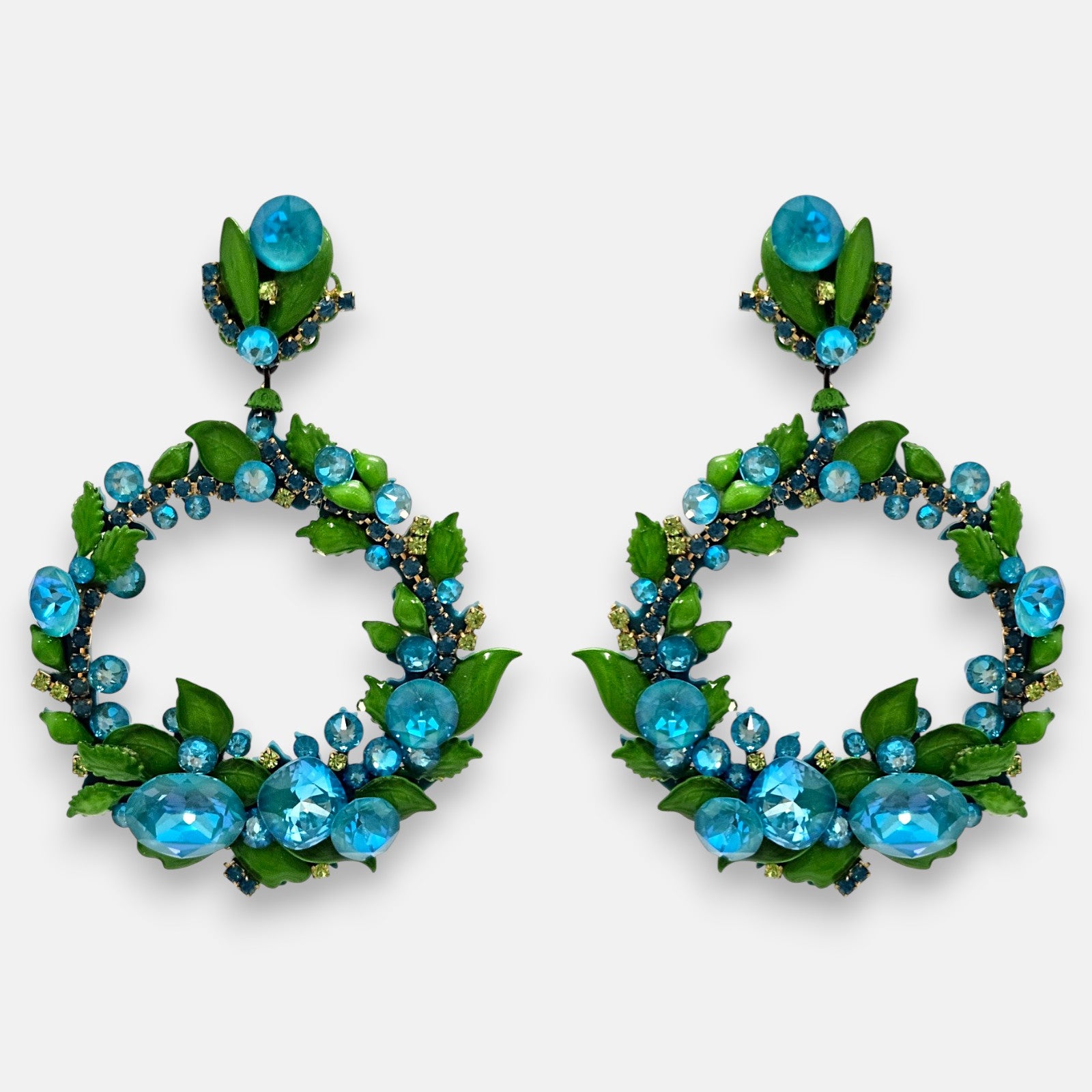 Pareja de pendientes de fiesta grandes en forma de aro abierto Soberanía de Capri de Dublos, mostrando su pedrería azul zafiro y su fleco inferior de cristales.