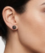 Primer plano de mujer luciendo los pendientes de botón marrones de Bohemme, resaltando su brillo cálido y elegante.