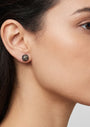Mujer luciendo los pendientes de botón azules de Bohemme, resaltando su brillo intenso y diseño elegante.