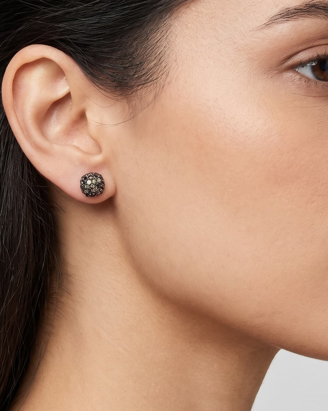 Mujer luciendo los pendientes de botón azules de Bohemme, resaltando su brillo intenso y diseño elegante.