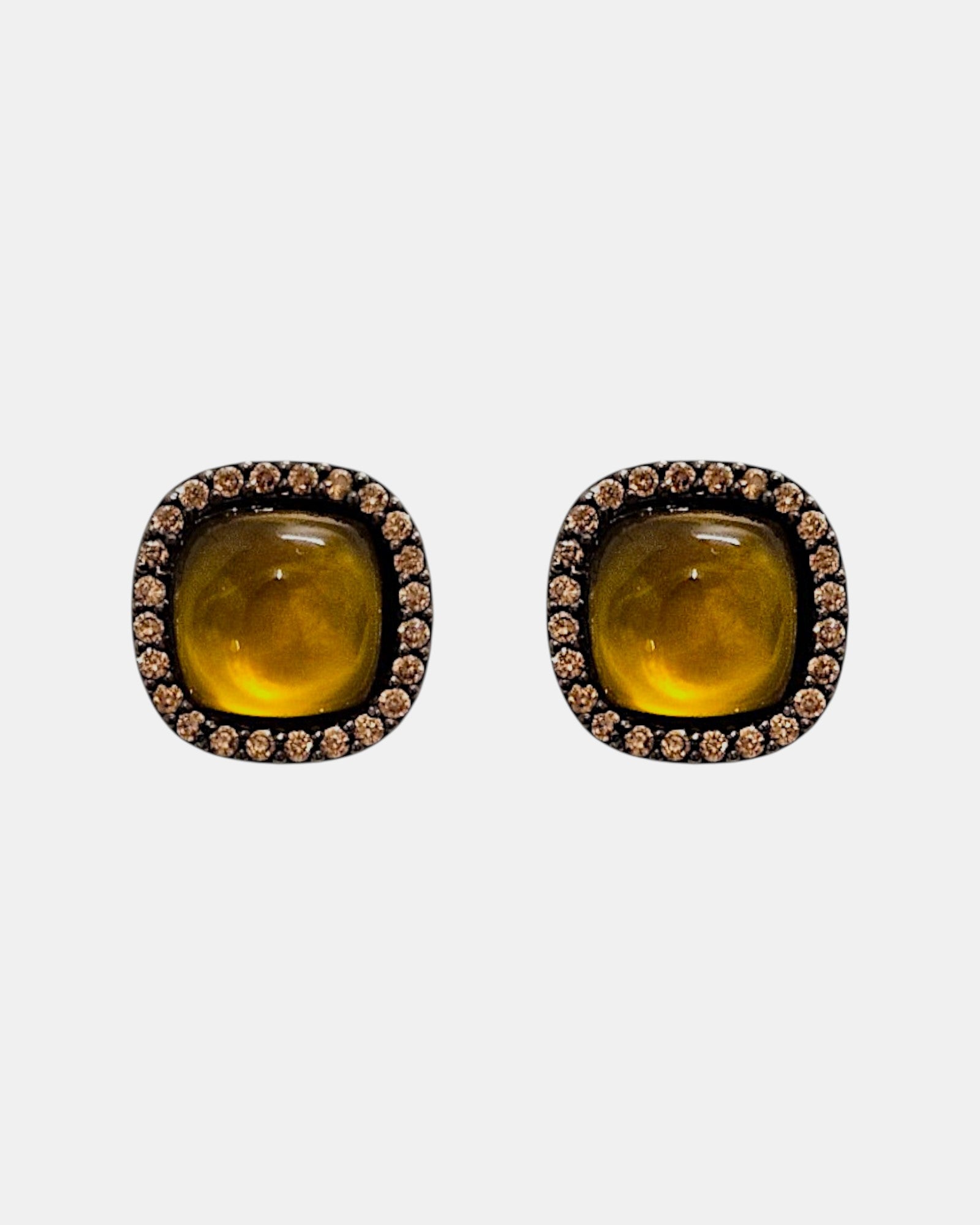 Pareja de pendientes de botón Bohemme con cabujón central color miel y orla de circonitas sobre plata oxidada.