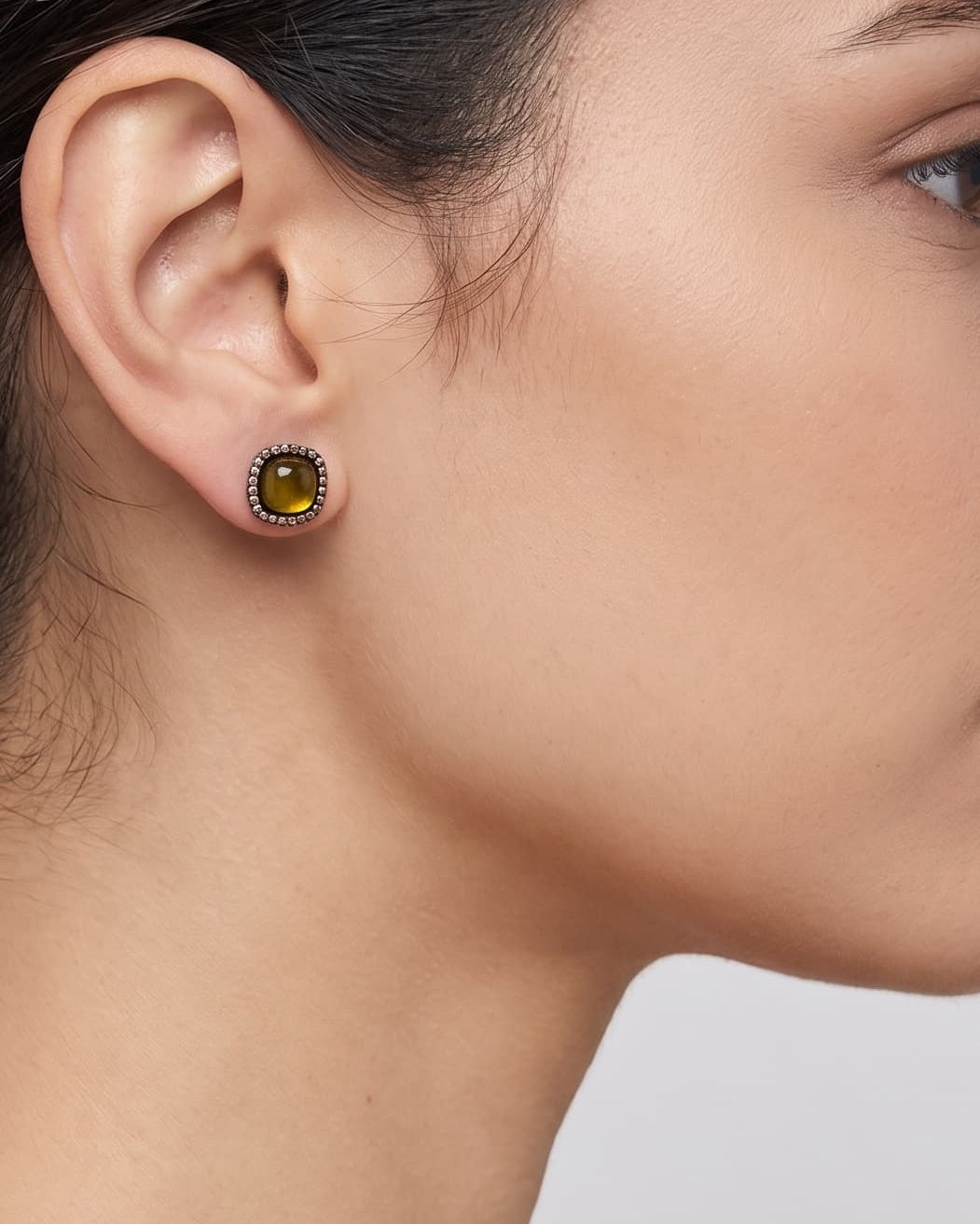 Mujer luciendo los pendientes Bohemme Amber Halo, destacando el brillo cálido de la gema ambarina en el lóbulo.