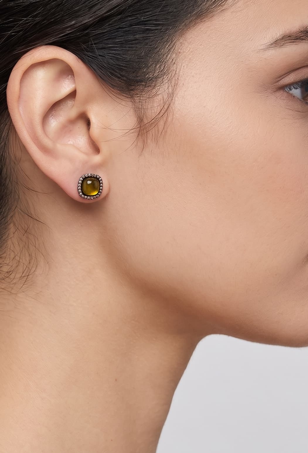 Mujer luciendo los pendientes Bohemme Amber Halo, destacando el brillo cálido de la gema ambarina en el lóbulo.