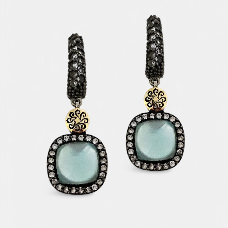 Pareja de pendientes Bohemme Hechizo con piedra central azul cabujón, pavé de circonitas y detalle en oro.