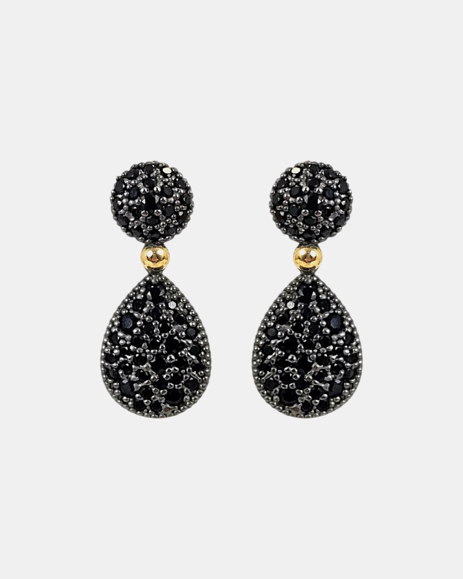 Pareja de pendientes articulados Bohemme con botón y lágrima en pavé de espinelas negras sobre fondo gris claro.