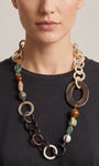 Mujer luciendo el collar Amlé, resaltando la asimetría del diseño y la mezcla de piedras naturales sobre un top oscuro.