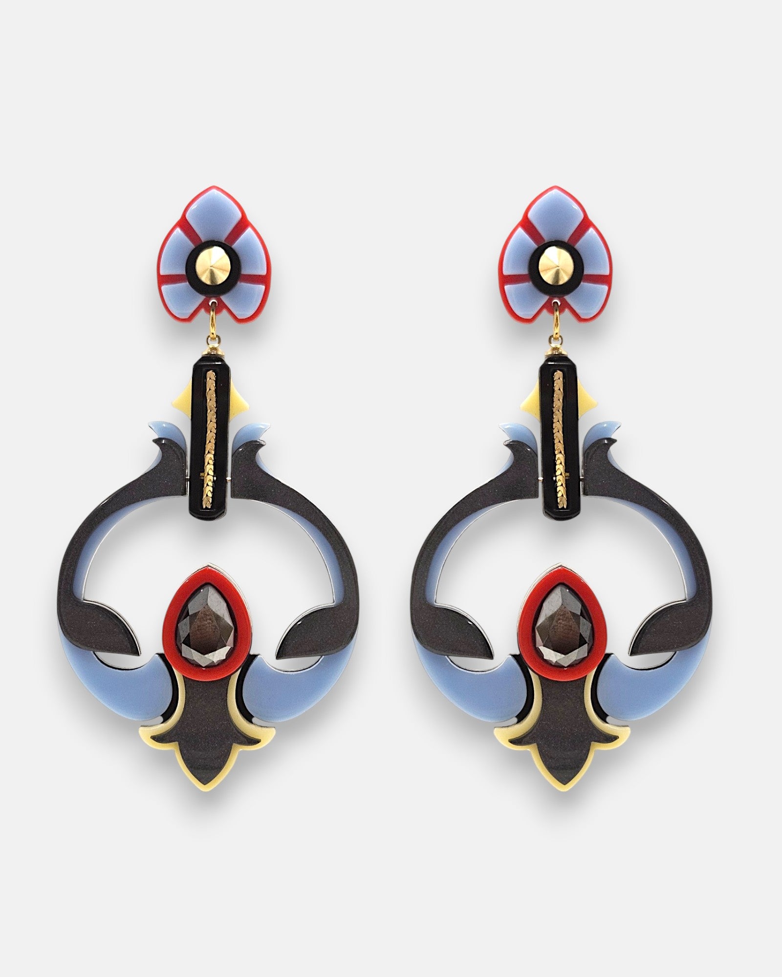 Pareja de pendientes grandes geométricos de Gissa Bicalho en acrílico, con forma de flor abstracta en color azul cielo, negro, rojo y líneas de oro.