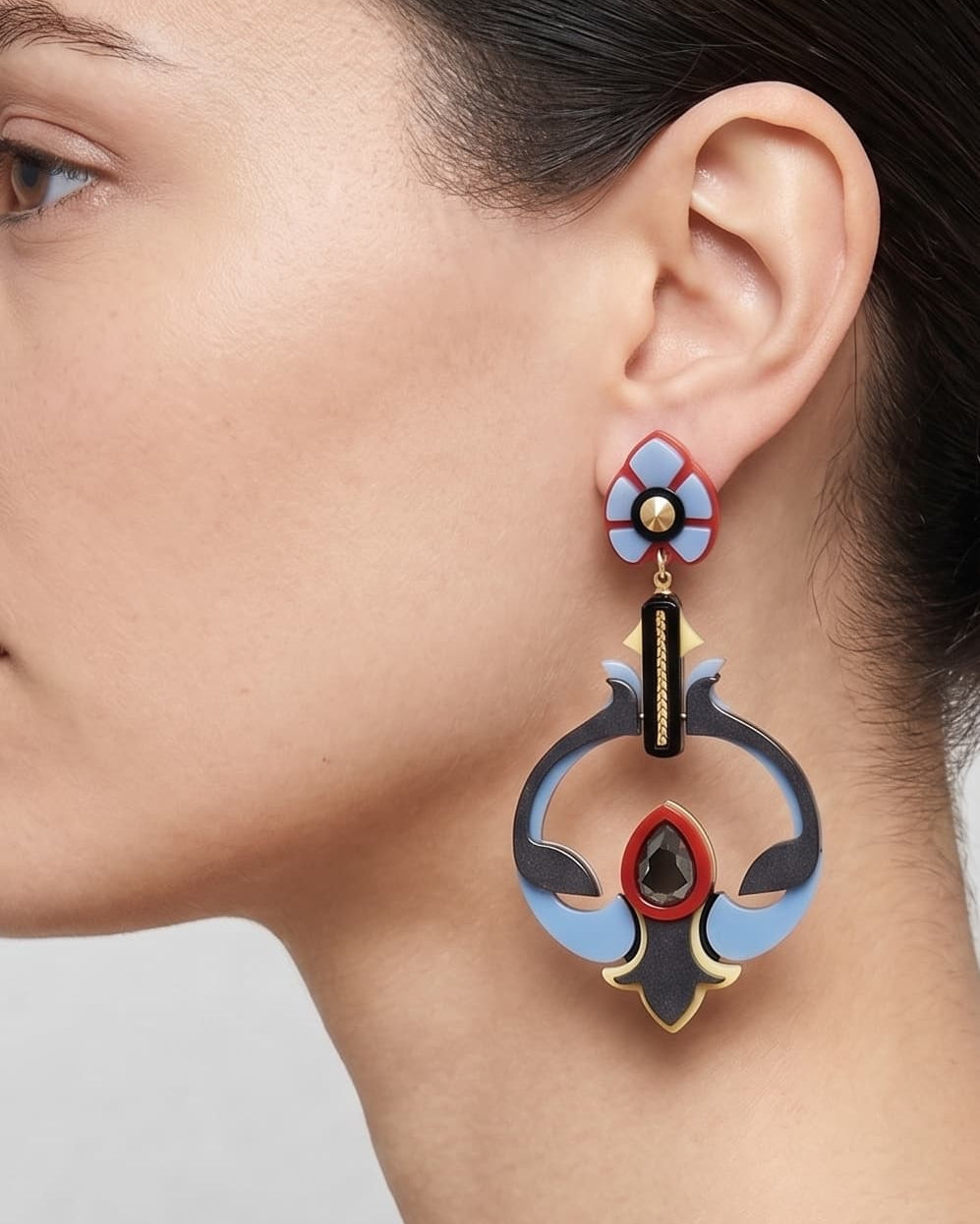 Vista de perfil de los pendientes escultóricos de acrílico de Gissa Bicalho colocados en una modelo, detallando su caída de aire Art Déco y su proporción maxi.