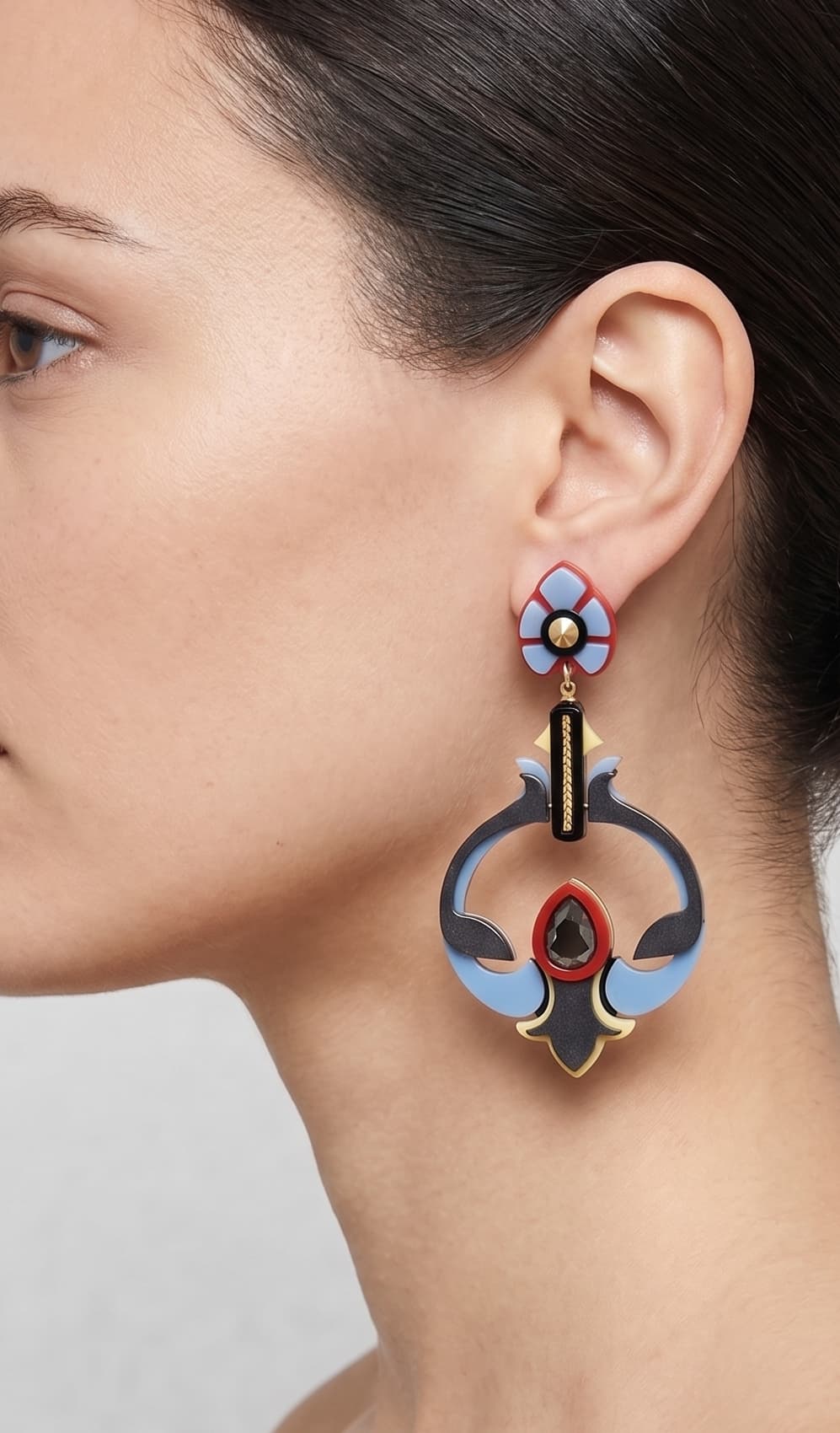 Vista de perfil de los pendientes escultóricos de acrílico de Gissa Bicalho colocados en una modelo, detallando su caída de aire Art Déco y su proporción maxi.