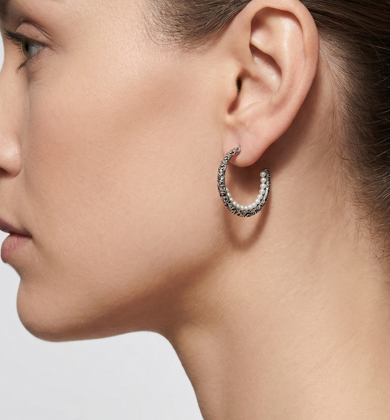 Mujer luciendo los pendientes de aro medio Maria e Luisa, resaltando el brillo de las perlas blancas y la textura de la plata.