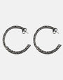 Pendientes de aro en plata de ley envejecida con
grabado calado artesanal de la marca Sanci sobre fondo gris claro.