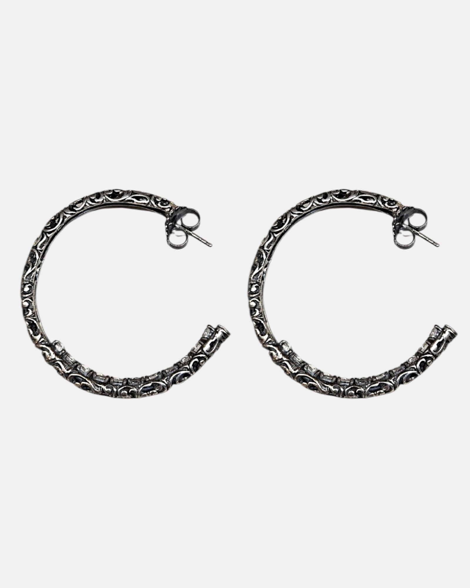 Pendientes de aro en plata de ley envejecida con
grabado calado artesanal de la marca Sanci sobre fondo gris claro.