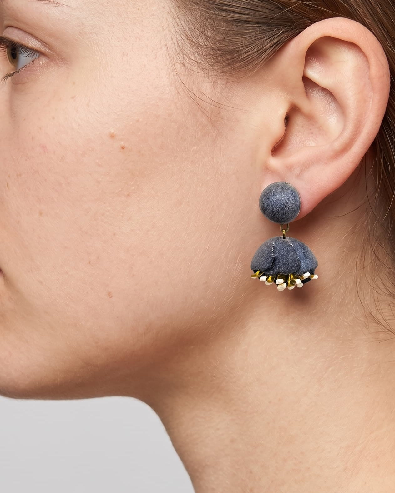 Vista de perfil de los pendientes de concha rosa de Ciléa Paris colocados en una modelo, detallando su tamaño compacto y cómo asientan sobre el lóbulo con su cómodo sistema de pinza.