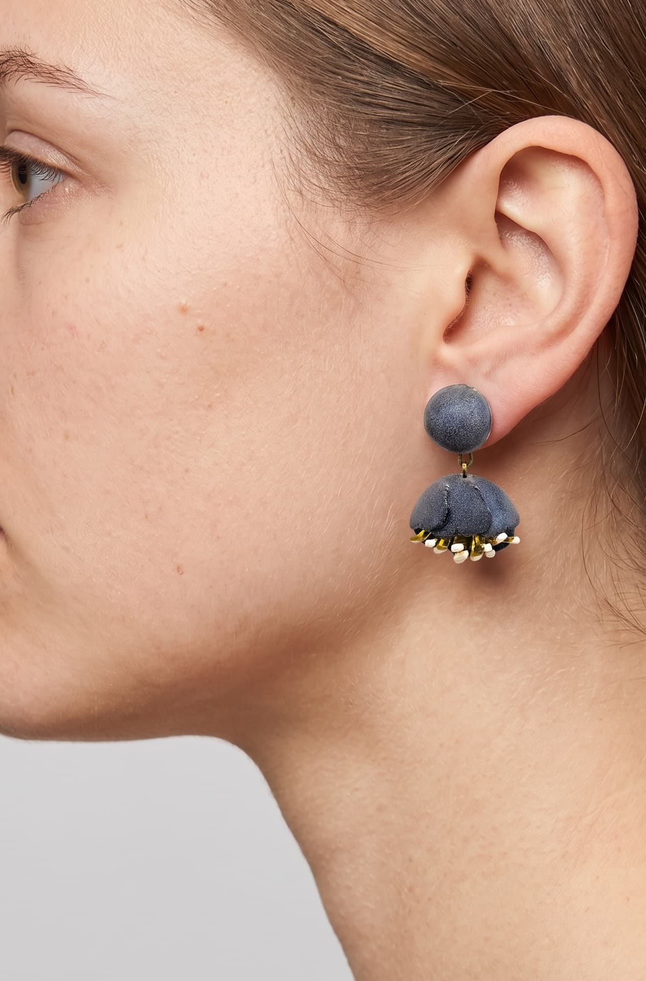 Vista de perfil de los pendientes de concha rosa de Ciléa Paris colocados en una modelo, detallando su tamaño compacto y cómo asientan sobre el lóbulo con su cómodo sistema de pinza.