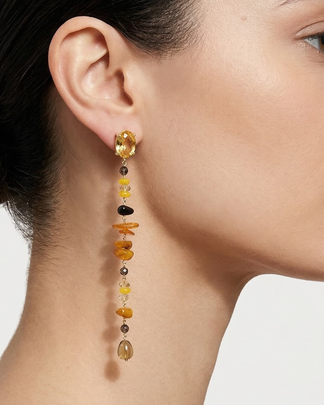 Mujer luciendo los pendientes largos lineales de Amlé, destacando cómo su silueta vertical estiliza el cuello y el rostro.