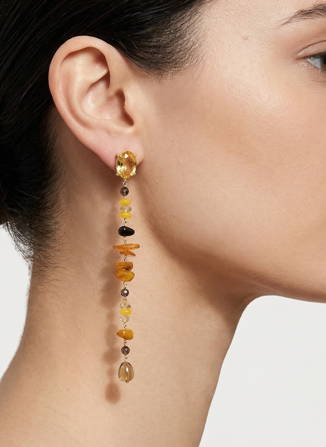Mujer luciendo los pendientes largos lineales de Amlé, destacando cómo su silueta vertical estiliza el cuello y el rostro.