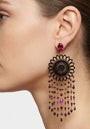 Mujer luciendo los pendientes maxi Amlé de estilo barroco, destacando el contraste entre el cuerno negro y las gemas de color rubí.