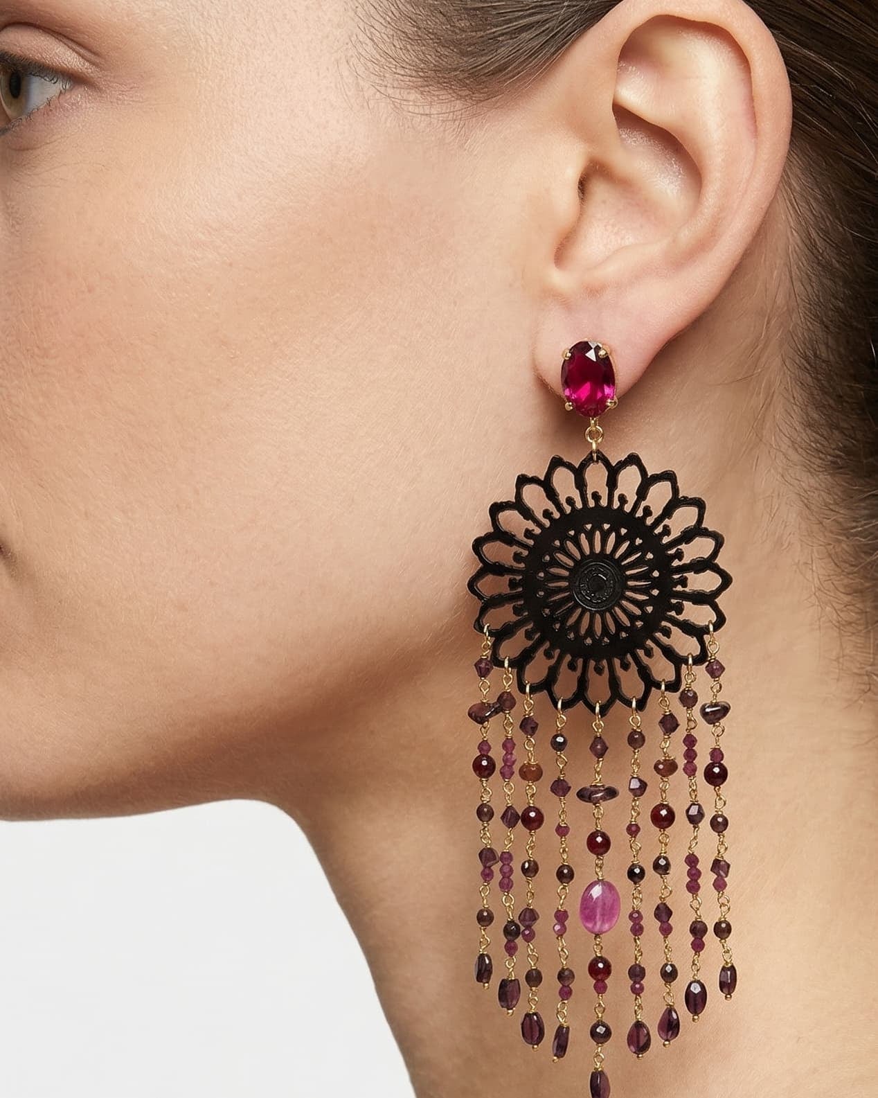 Mujer luciendo los pendientes maxi Amlé de estilo barroco, destacando el contraste entre el cuerno negro y las gemas de color rubí.