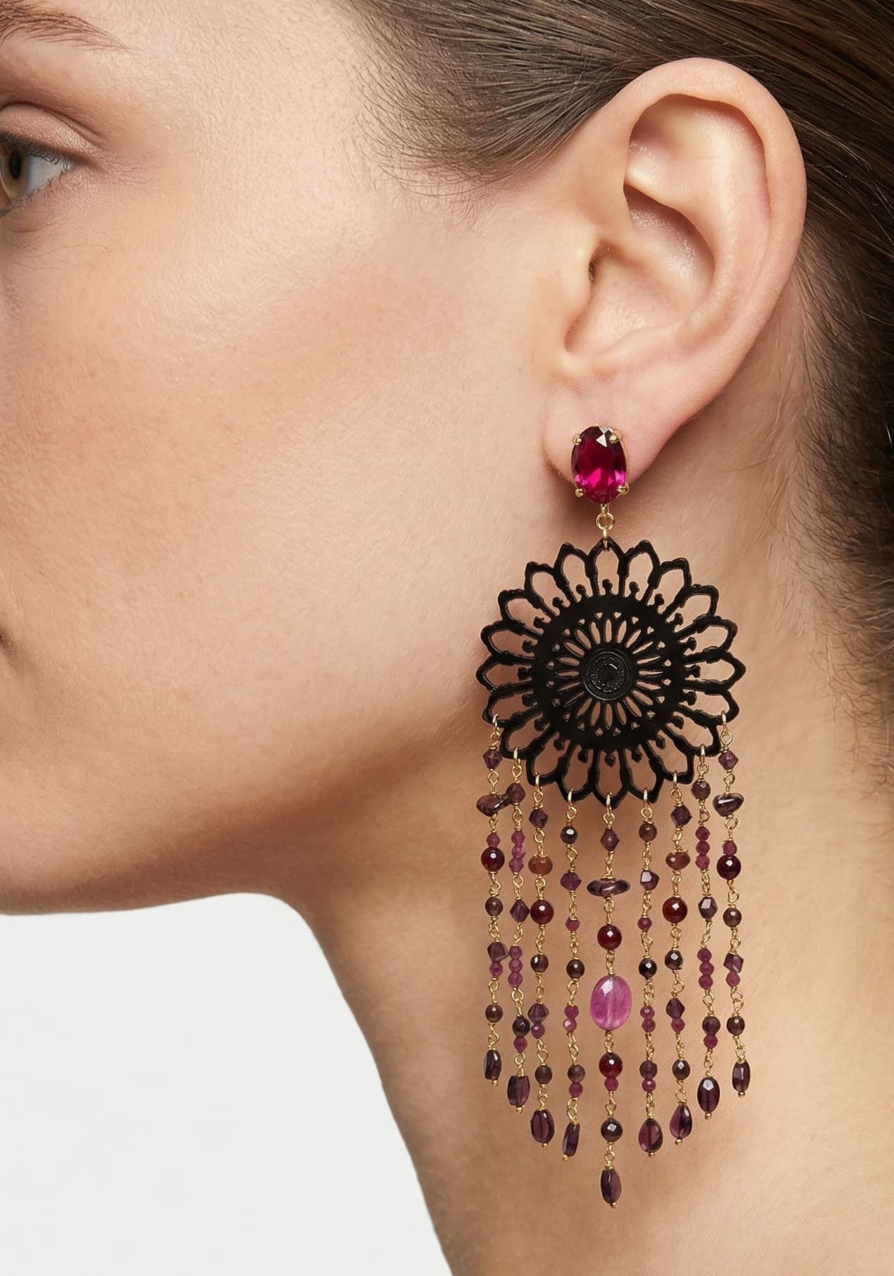 Mujer luciendo los pendientes maxi Amlé de estilo barroco, destacando el contraste entre el cuerno negro y las gemas de color rubí.