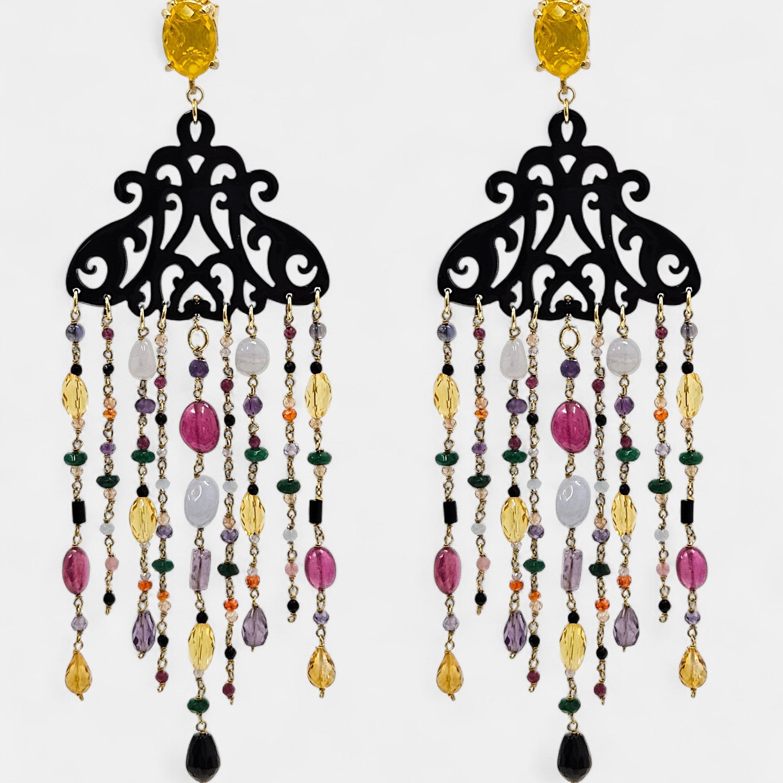 Pendientes largos Amlé de cuerno negro calado con cascada de piedras naturales multicolores sobre fondo blanco.