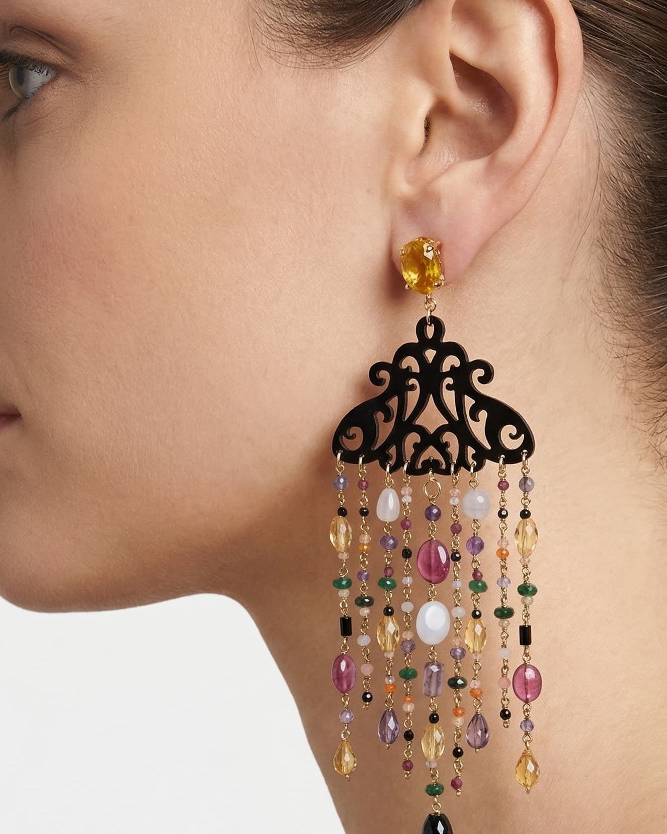 Mujer luciendo los pendientes Amlé de estilo italiano, resaltando el movimiento de las gemas y el detalle del cuerno.