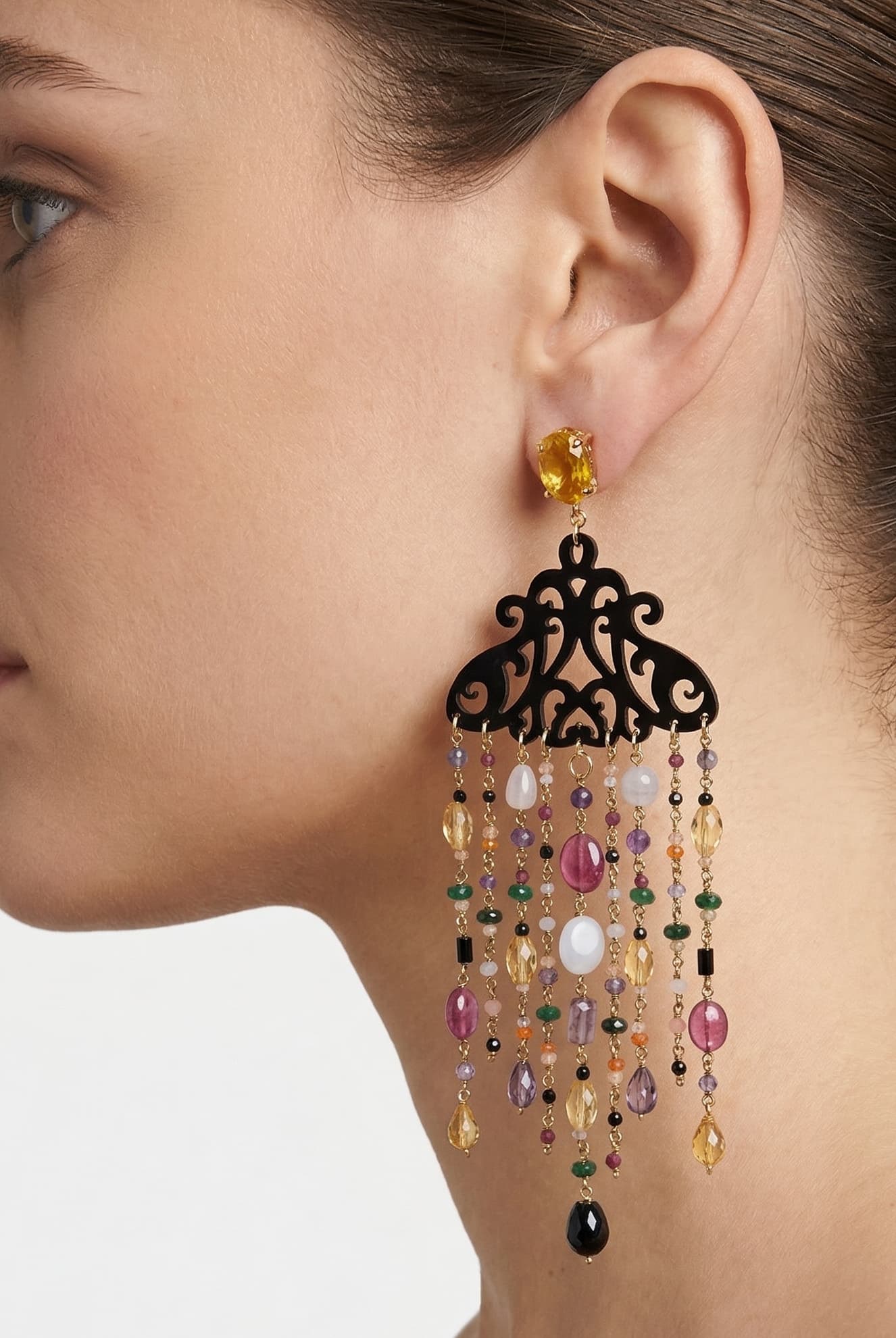 Mujer luciendo los pendientes Amlé de estilo italiano, resaltando el movimiento de las gemas y el detalle del cuerno.