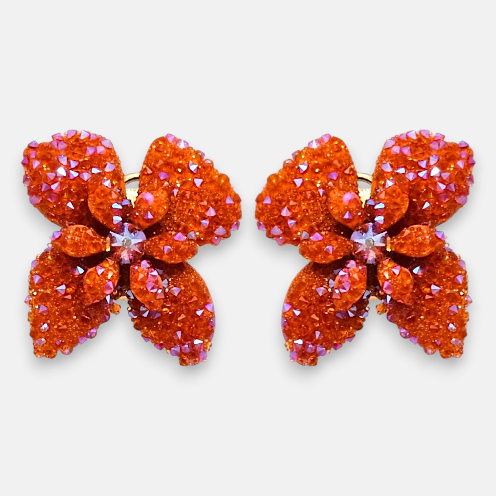 Pareja de pendientes de botón en forma de flor naranja mandarina de la firma Dublos, mostrando su silueta de cuatro pétalos con cristales iridiscentes.
