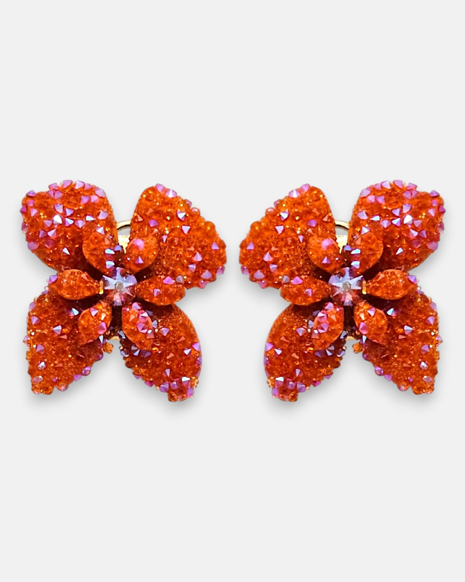 Pareja de pendientes de botón en forma de flor naranja mandarina de la firma Dublos, mostrando su silueta de cuatro pétalos con cristales iridiscentes.