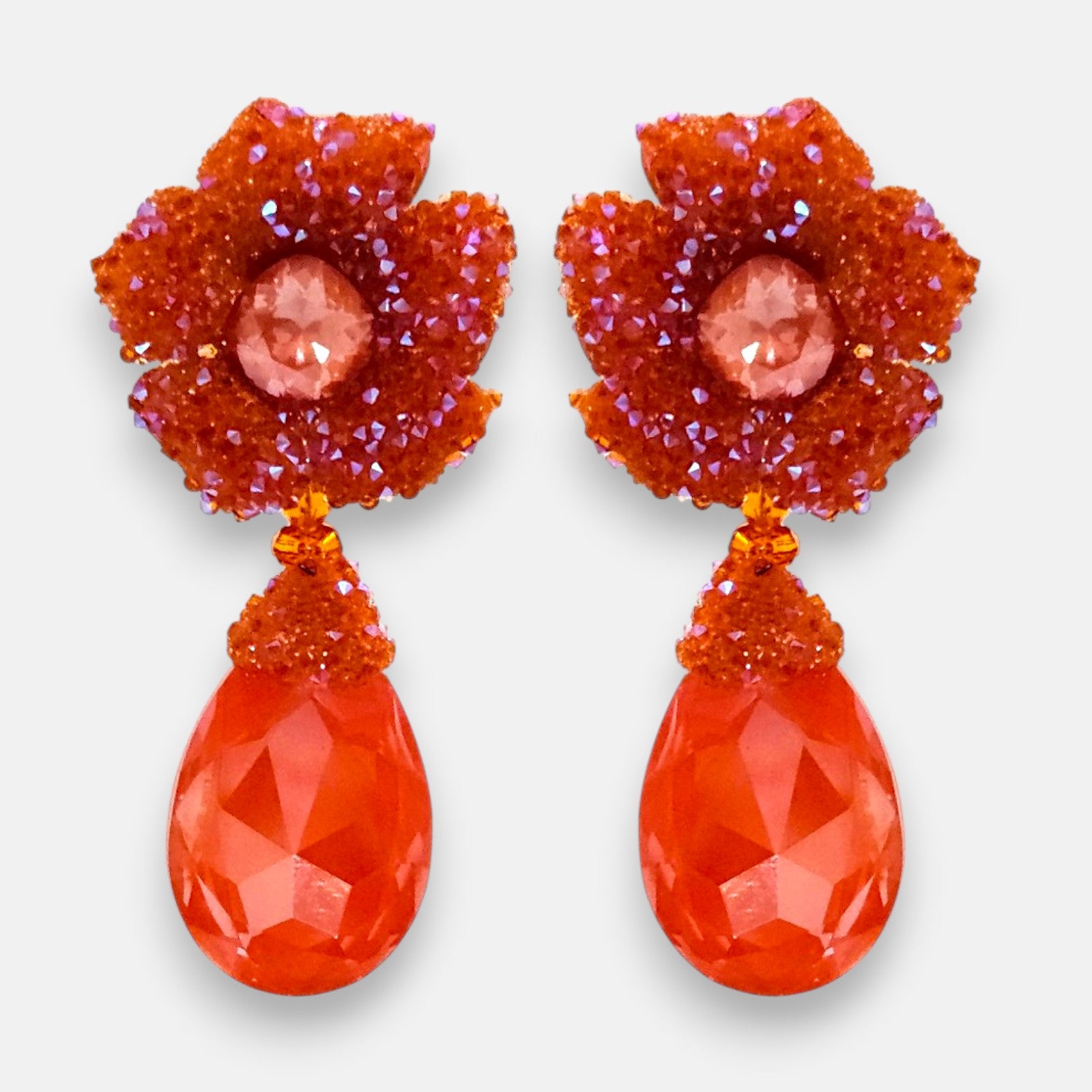 Pareja de pendientes de fiesta grandes Flor de Granada de Dublos, mostrando su botón superior de flor naranja mandarina y su gran lágrima facetada coral.