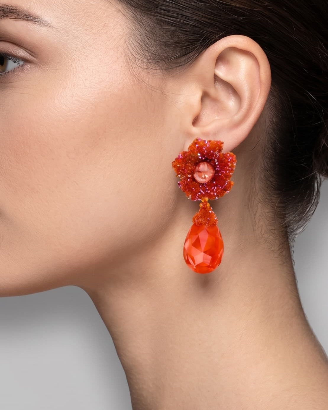 Vista de perfil de un maxipendiente colgante naranja de Dublos colocado en una modelo, detallando la caída y el volumen de la lágrima de cristal.