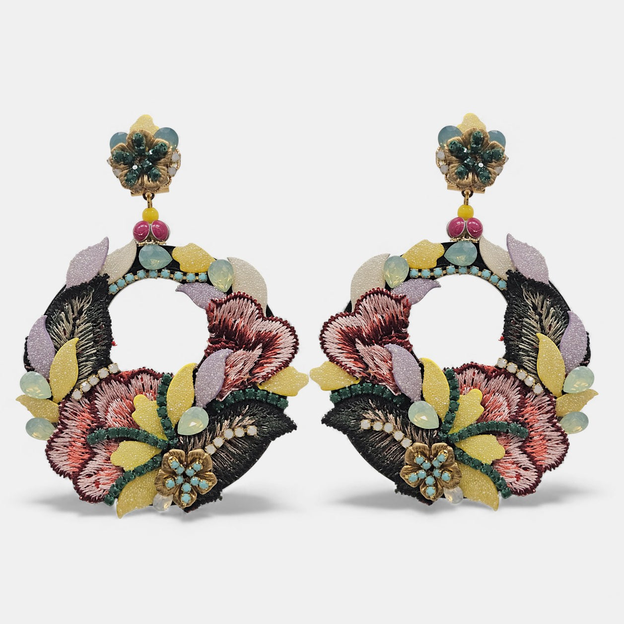 Pareja de pendientes Dublos circulares con bordado de seda floral en tonos malva y granate sobre fondo gris claro.