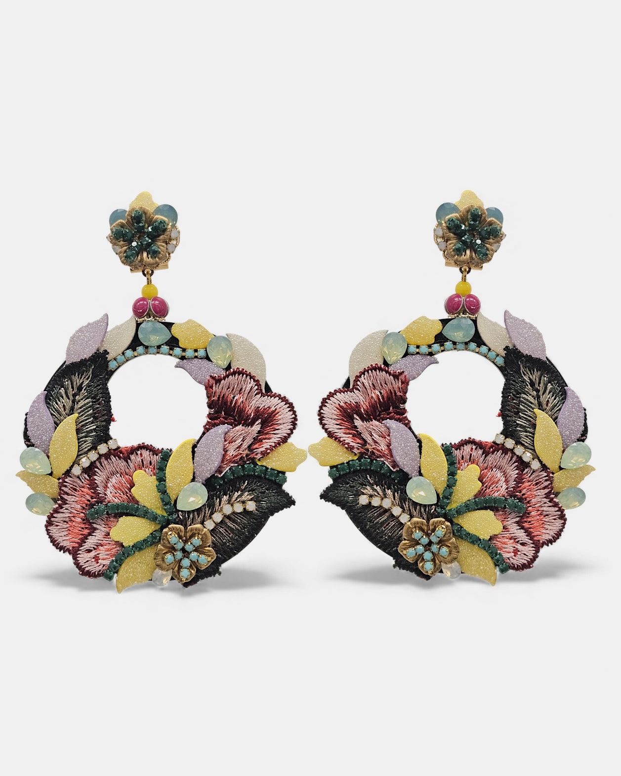 Pareja de pendientes Dublos circulares con bordado de seda floral en tonos malva y granate sobre fondo gris claro.