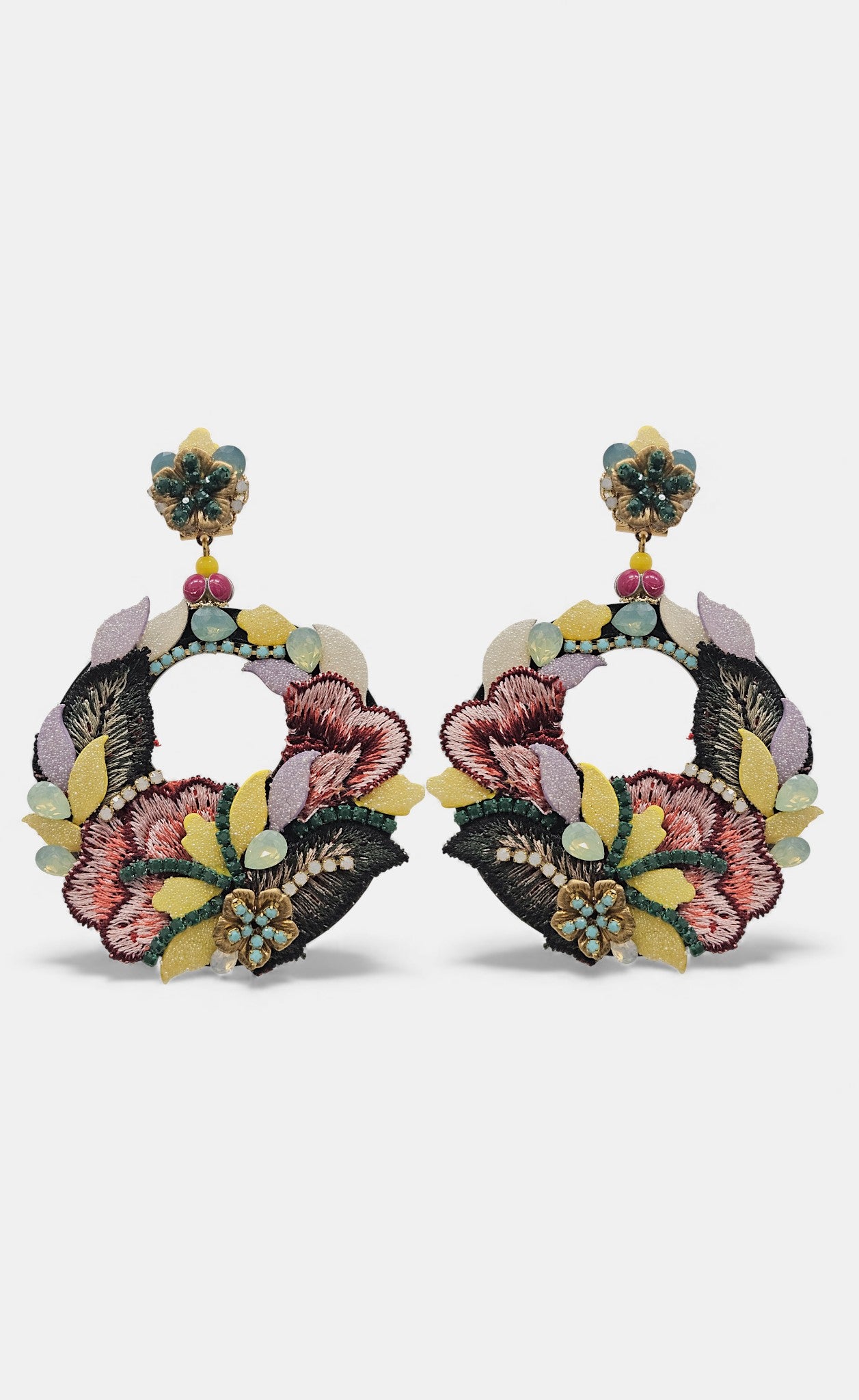 Pareja de pendientes Dublos circulares con bordado de seda floral en tonos malva y granate sobre fondo gris claro.