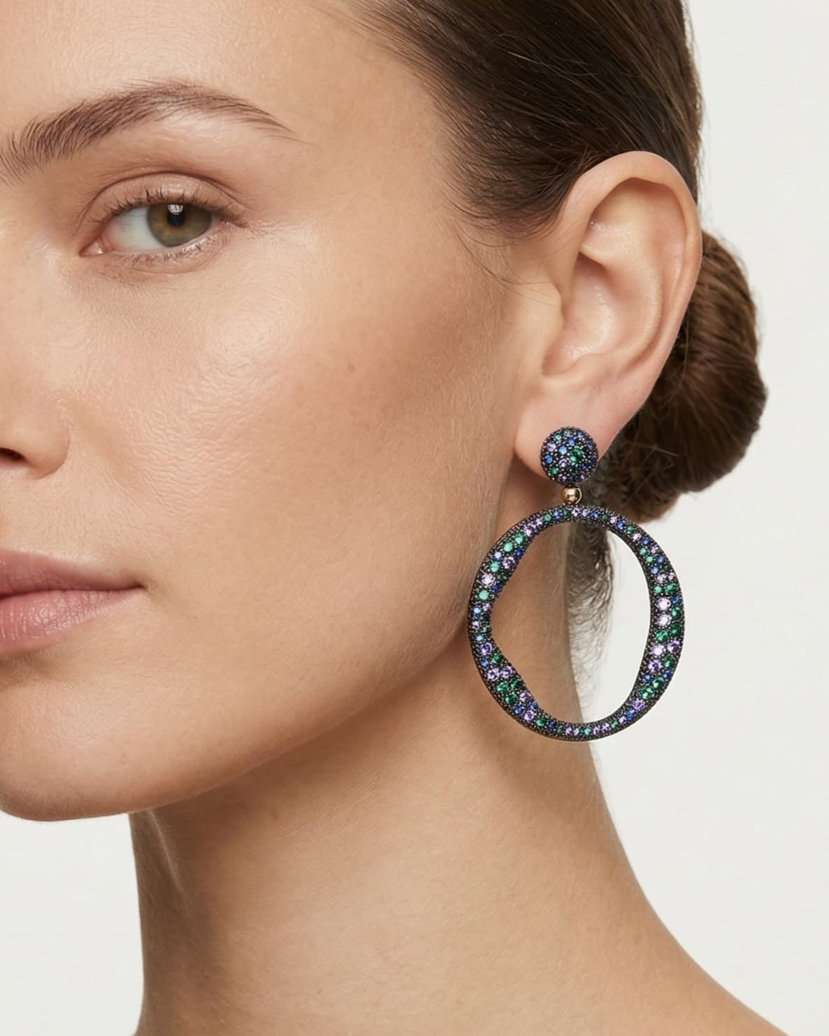 Mano de mujer luciendo los pendientes de aro Bohemme Océano, resaltando su tamaño maxi y su brillo multicolor.