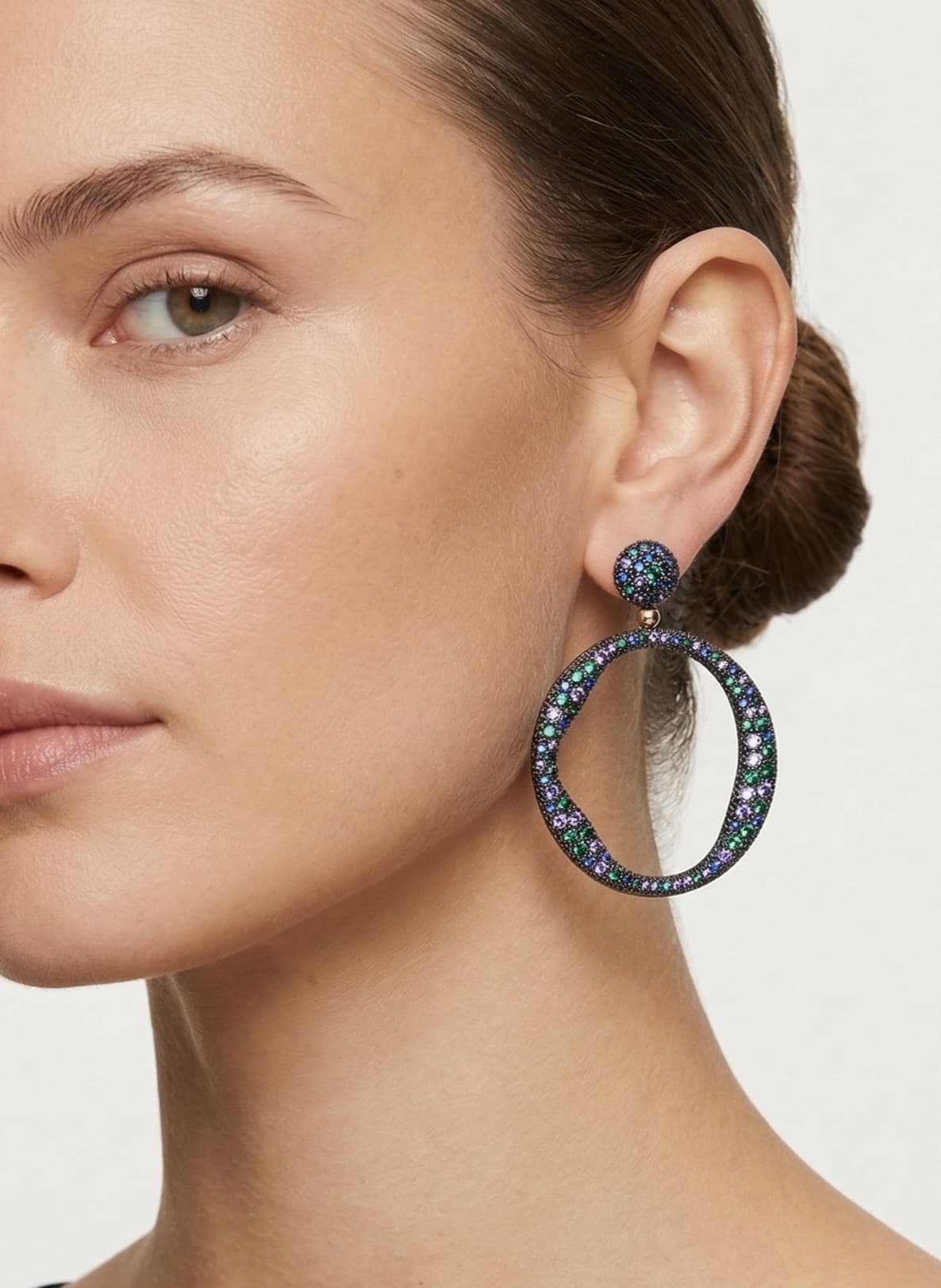 Mano de mujer luciendo los pendientes de aro Bohemme Océano, resaltando su tamaño maxi y su brillo multicolor.