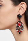 Primer plano de perfil de mujer luciendo los pendientes Dublos, resaltando la forma de lágrima y el brillo intenso del cristal rojo central.