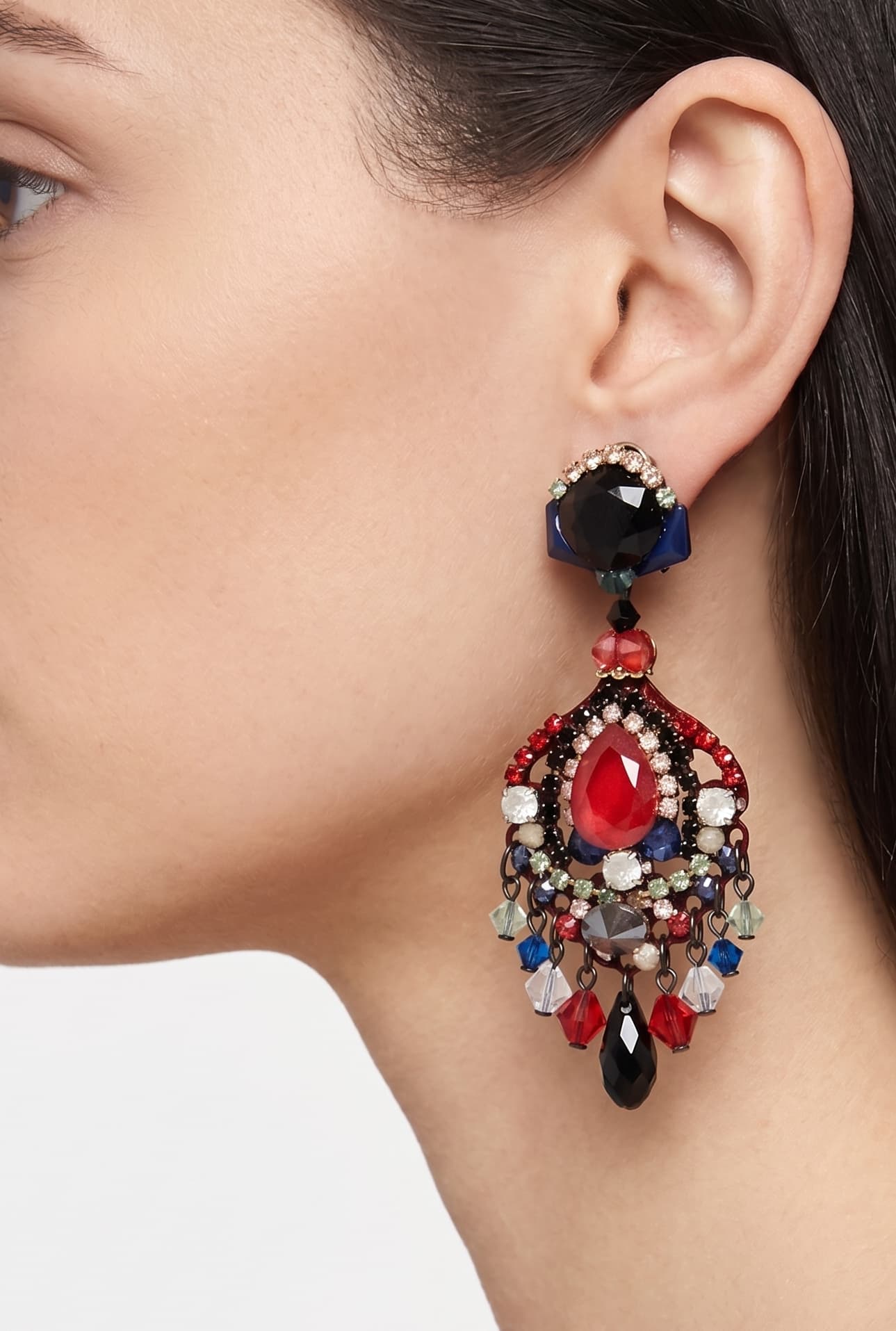Primer plano de perfil de mujer luciendo los pendientes Dublos, resaltando la forma de lágrima y el brillo intenso del cristal rojo central.