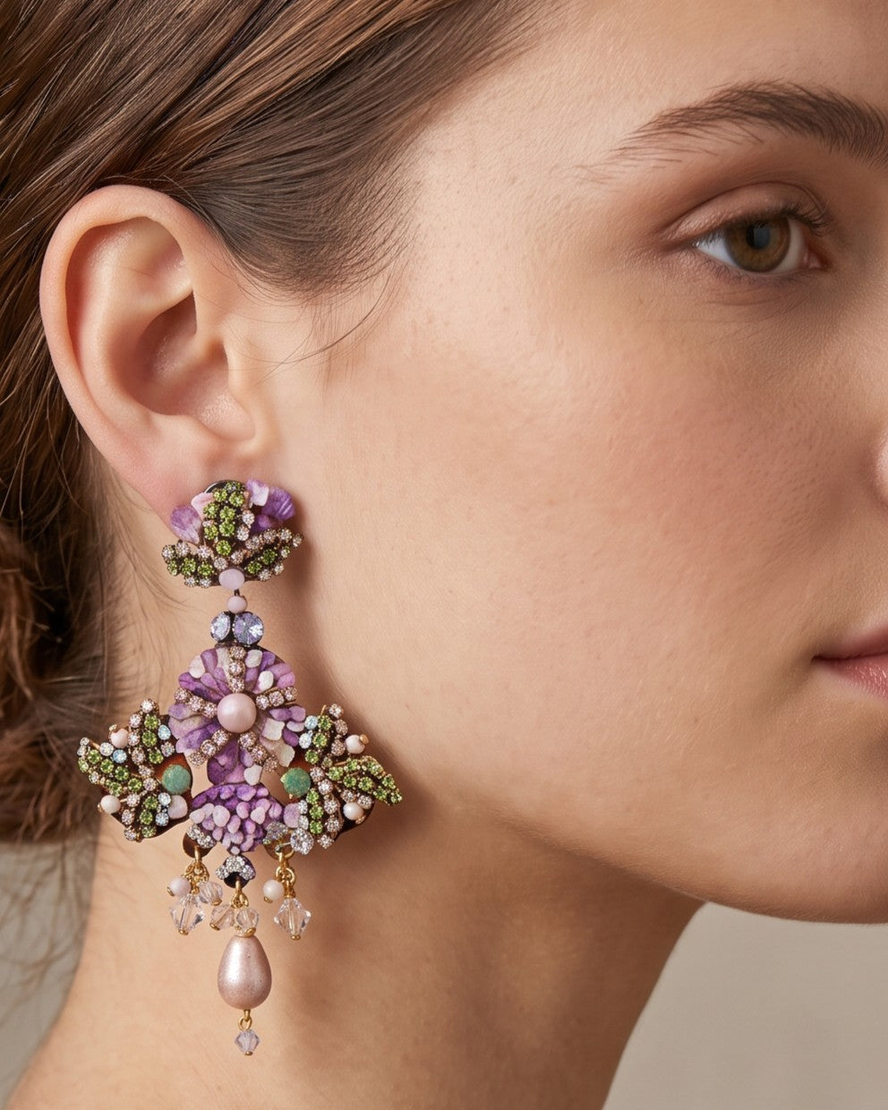  modelo luciendo el Pendiente Cruz Floral Malva de Dublos, apreciando la escala, el enmarque sobre el rostro y las lágrimas colgantes.   