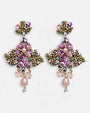 par de Pendientes Cruz Floral Malva de Dublos dispuesto sobre fondo blanco.   