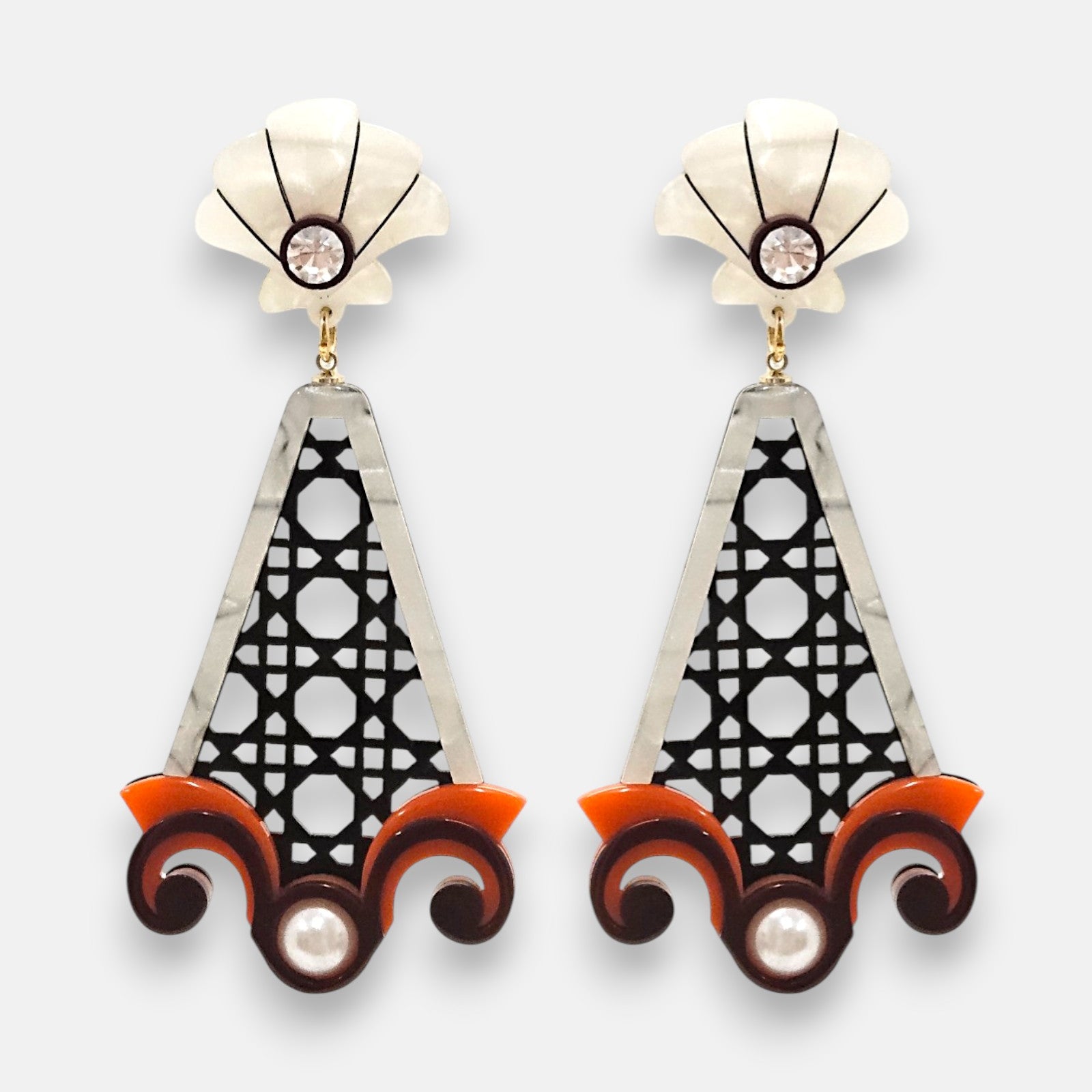 Pareja de pendientes grandes de Gissa Bicalho con cuerpo calado negro tipo rejilla cannage, base de volutas naranja y marrón con perla, y botón superior nácar con cristal.