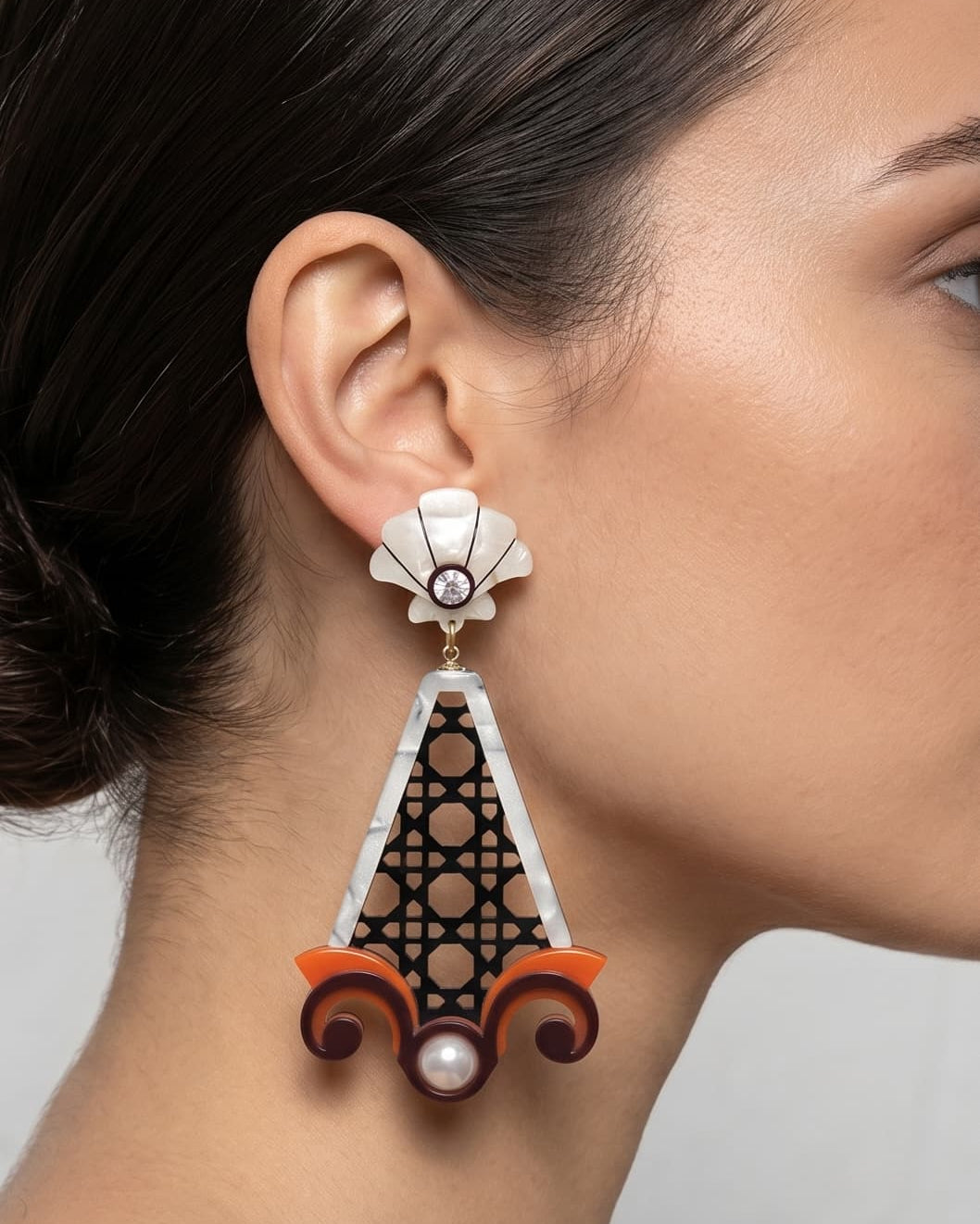 Vista de perfil de los maxi pendientes de acrílico de Gissa Bicalho colocados en una modelo, detallando su caída tridimensional de estilo arquitectónico y su gran escala.
