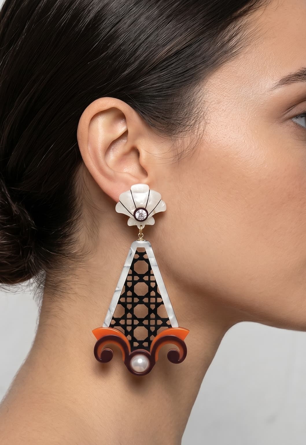 Vista de perfil de los maxi pendientes de acrílico de Gissa Bicalho colocados en una modelo, detallando su caída tridimensional de estilo arquitectónico y su gran escala.