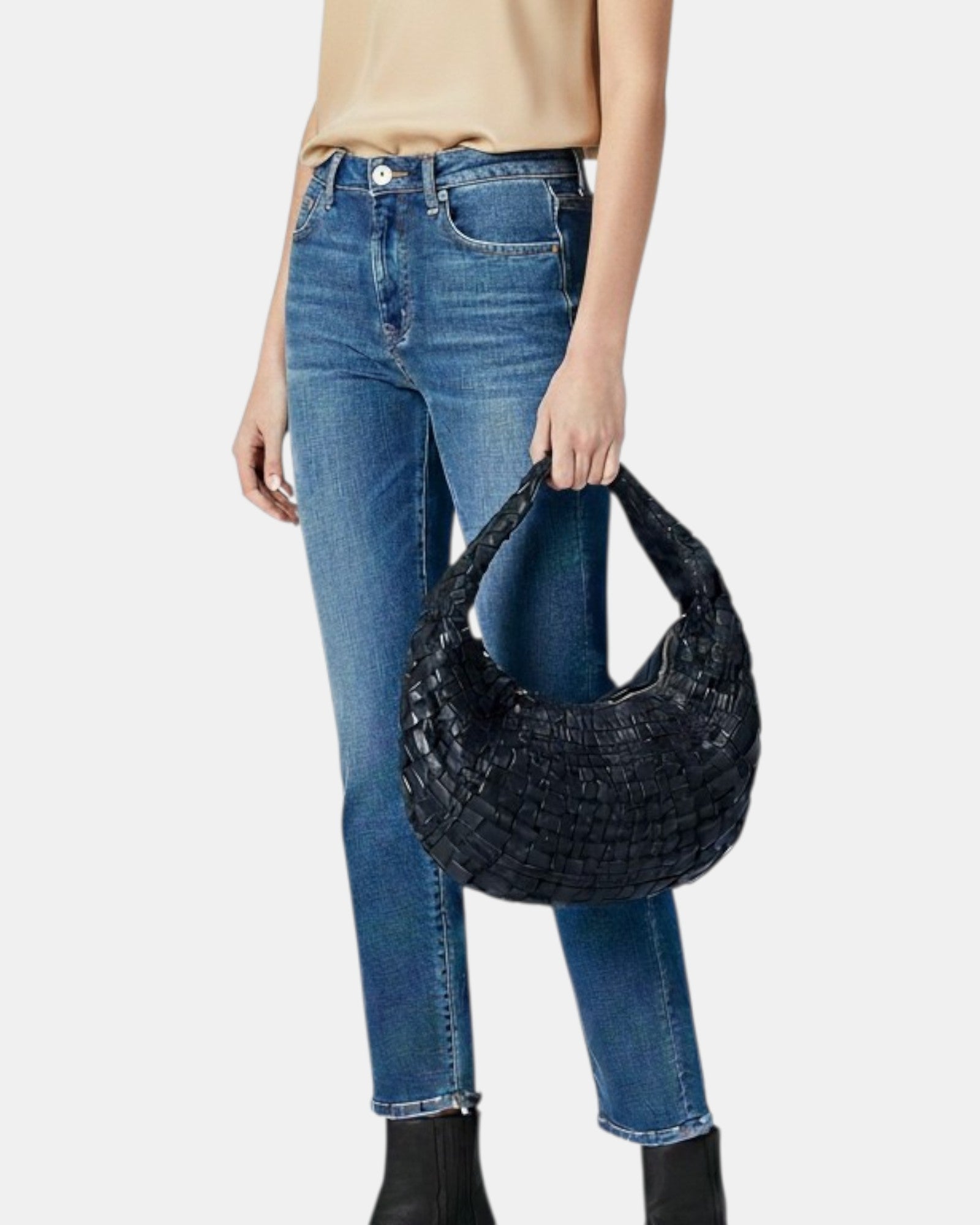 Bolso negro trenzado Sanci, jeans azules y blusa beige en fondo blanco