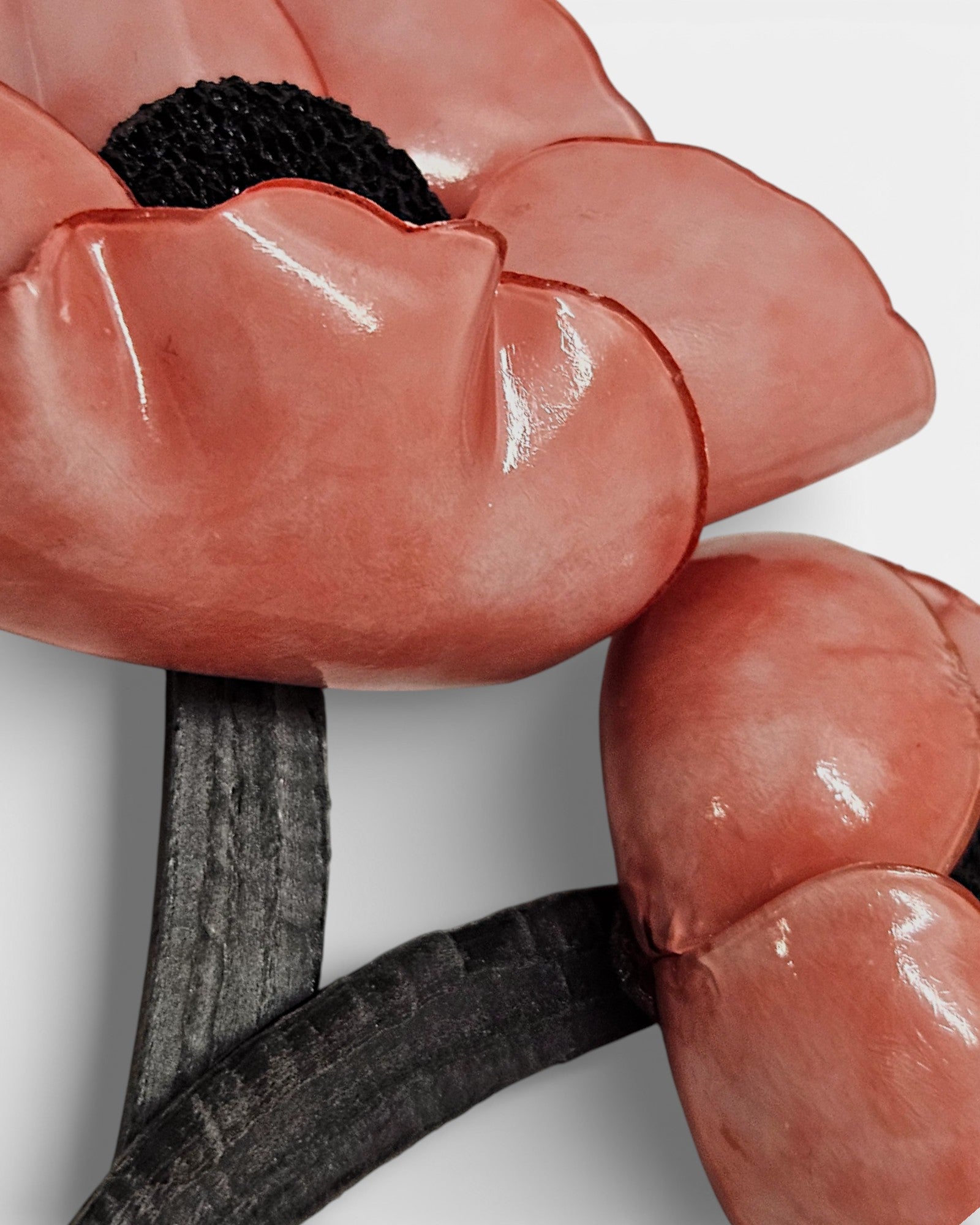 Detalle de pétalos rosas brillantes y centro negro de broche artesanal."