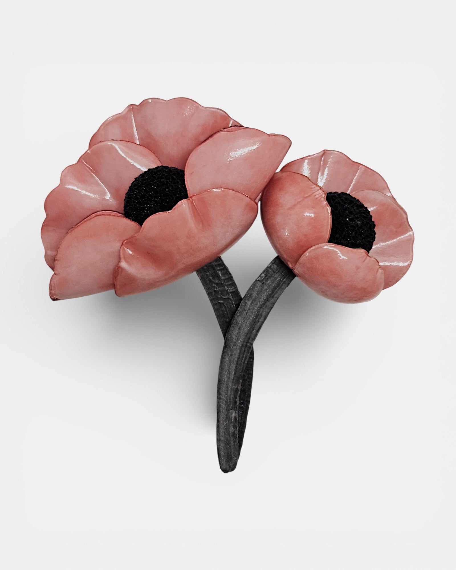 "Broche de dos flores amapolas en color rosa salmón con tallos negros sobre fondo blanco."
