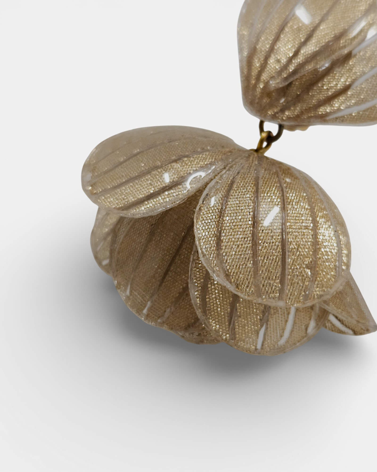 Pendiente dorado de Sanci con forma de pétalos sobre fondo blanco