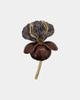 Broche en forma de flor con pétalos superiores grises texturizados y pétalos inferiores café brillante con bordes dorados sobre fondo blanco.