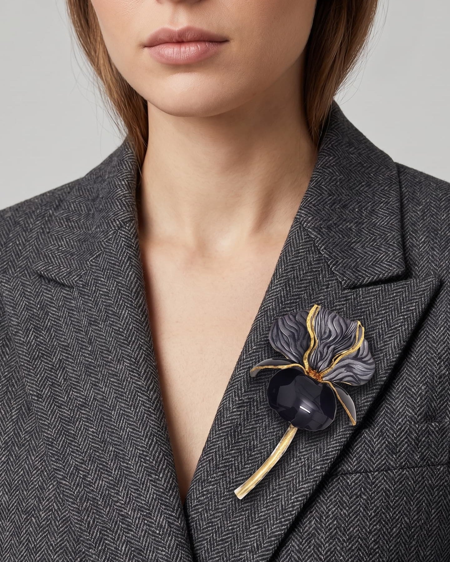 Vista lateral del maxibroche floral negro de Ciléa Paris prendido en una chaqueta de lana gris, detallando su silueta estilizada con tallo sobre la solapa.