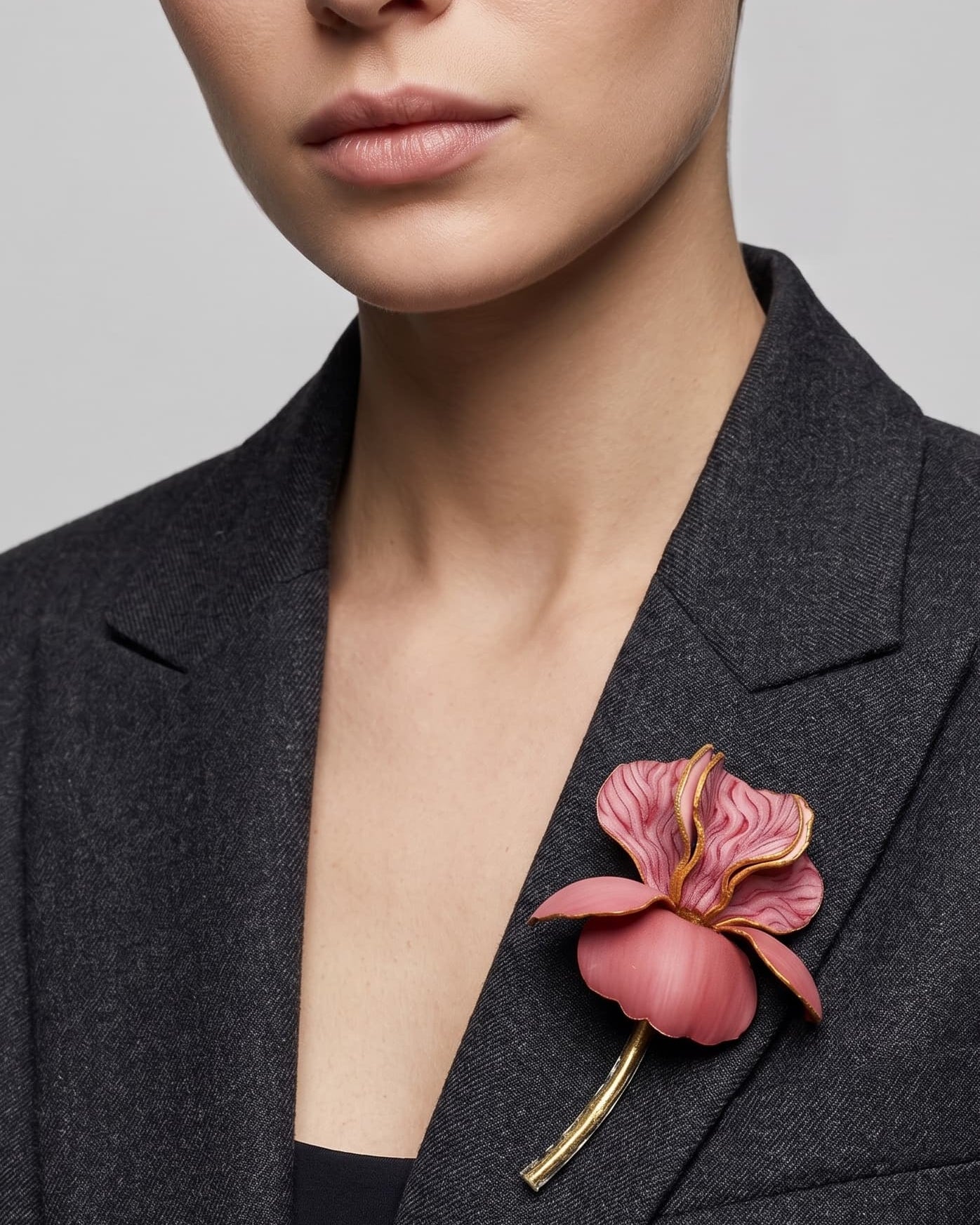 Vista frontal del maxibroche floral rosa de Ciléa Paris prendido en la solapa de una chaqueta de lana gris oscura, detallando su volumen y silueta estilizada.