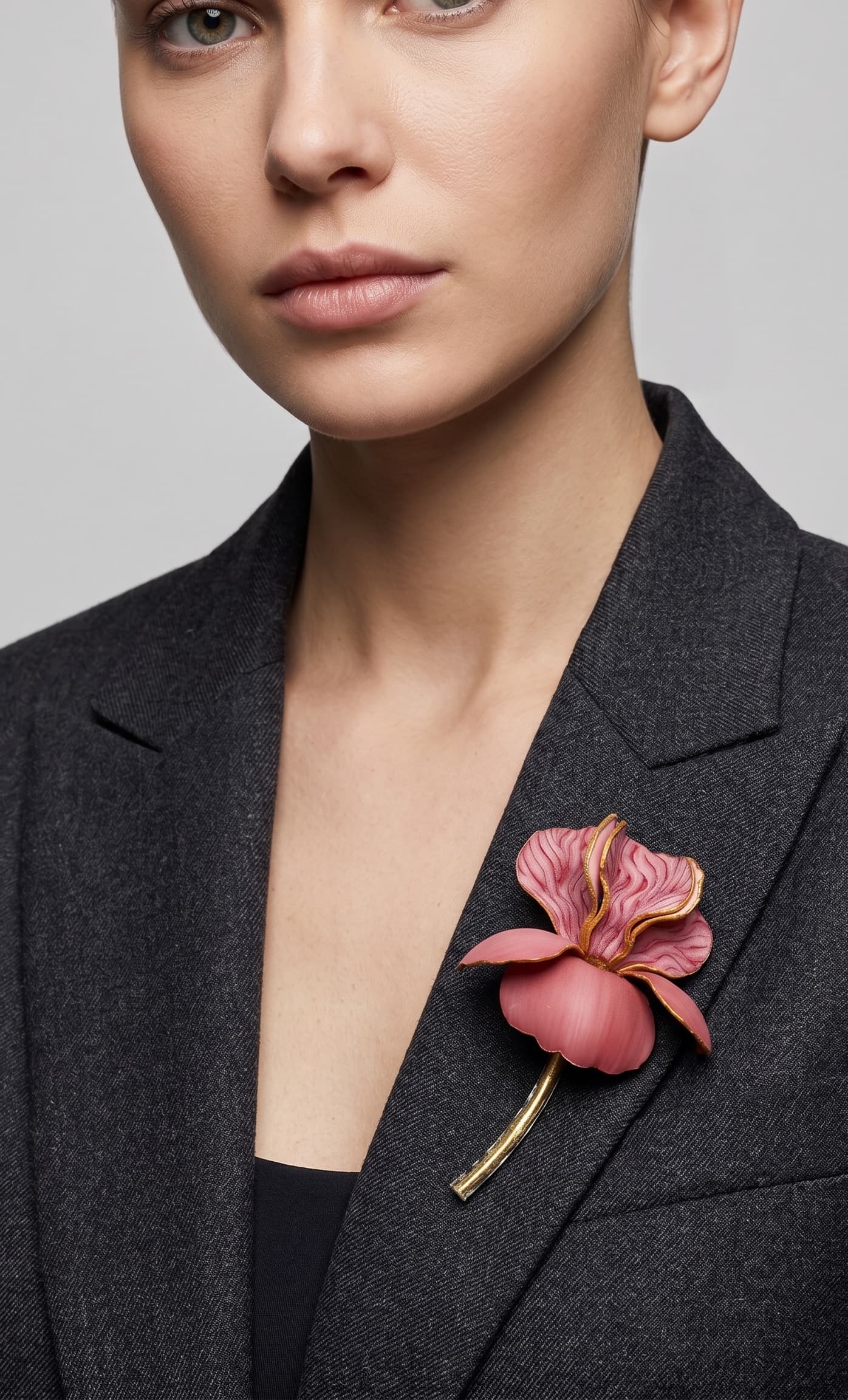 Vista frontal del maxibroche floral rosa de Ciléa Paris prendido en la solapa de una chaqueta de lana gris oscura, detallando su volumen y silueta estilizada.